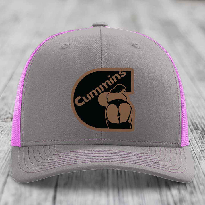 Grey trucker hat with yellow mesh sides and stitching, featuring a Cummins logo patch.