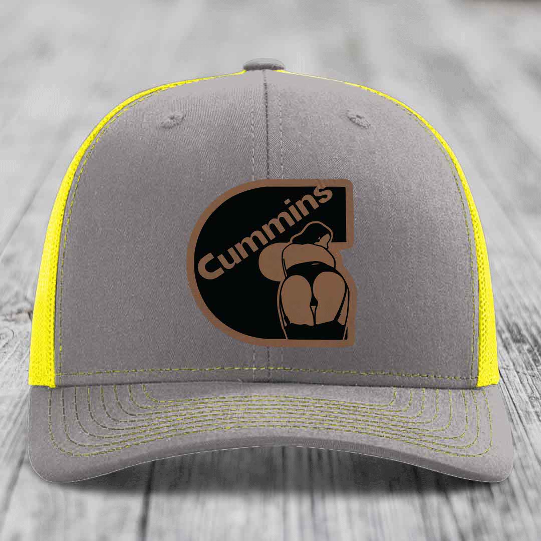 Brown trucker hat with black and tan Cummins logo patch on front, white mesh back.