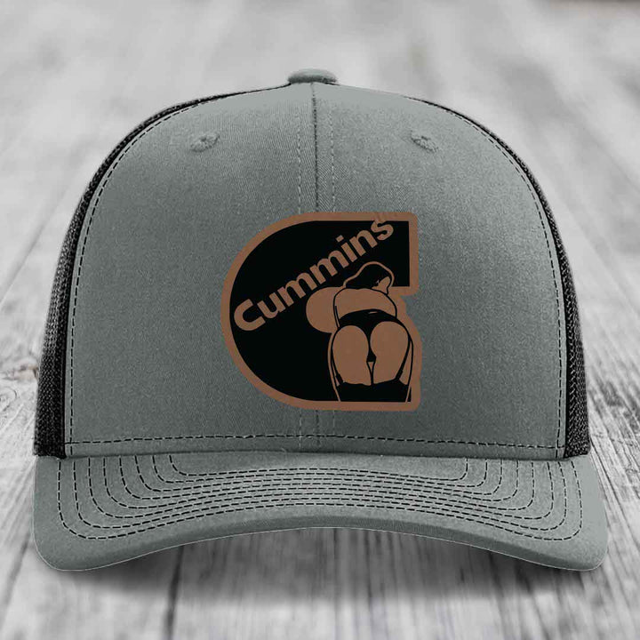 Grey trucker hat with white mesh back and embroidered Cummins logo patch.