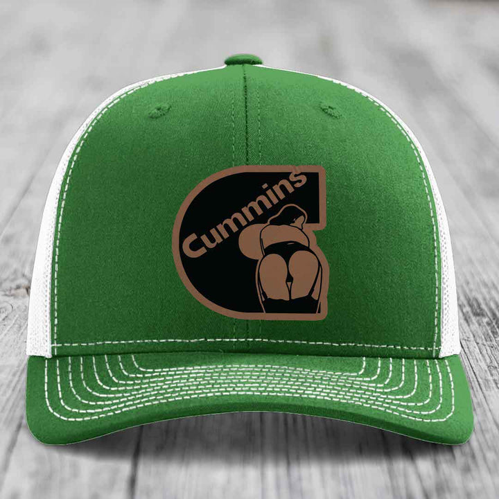 Beige trucker hat with black mesh back and brown leather patch featuring &