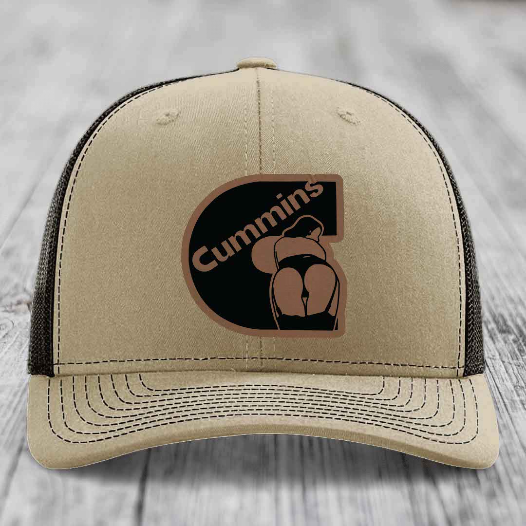Tan trucker hat with black and brown Cummins logo patch on front.