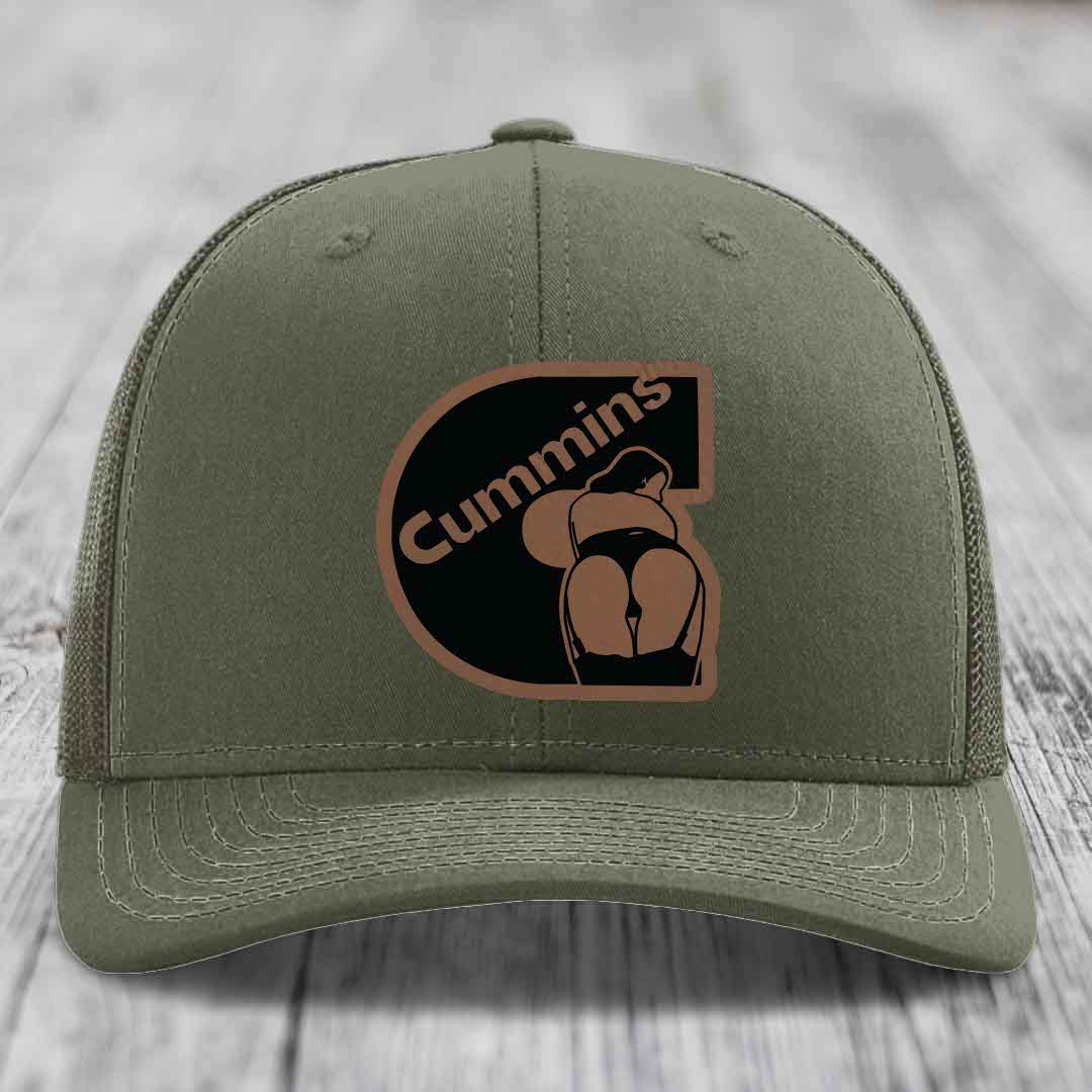 Olive green trucker hat with black mesh back and a brown leatherette patch featuring the Cummins logo.