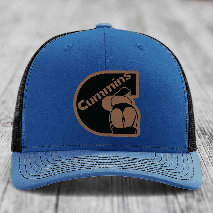 Blue and red trucker hat with Cummins logo patch on front, white mesh back, and white stitching.
