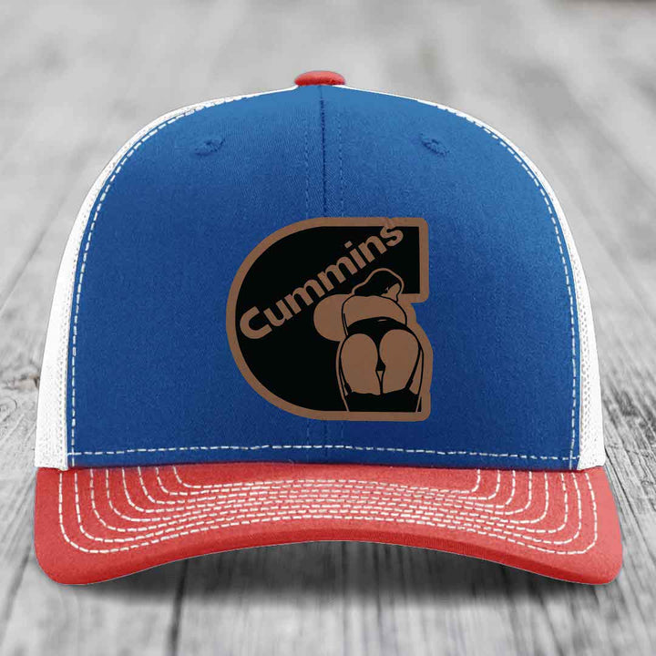 White trucker hat with brown and black Cummins logo patch featuring a stylized figure.