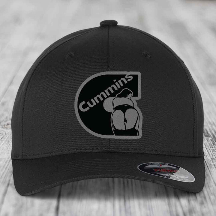 Tan baseball cap with black and grey Cummins logo patch on front, featuring a stylized &
