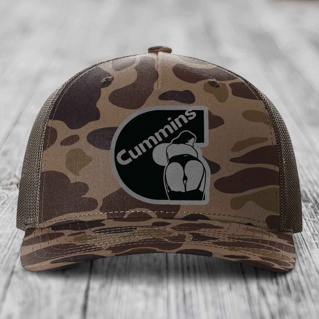 Camouflage trucker hat with black Cummins logo patch on front.