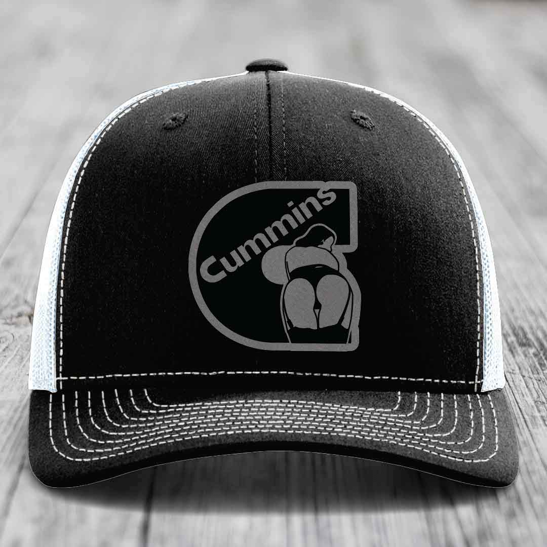 Black trucker hat with white mesh back and gray brim, featuring a gray Cummins logo patch on front.