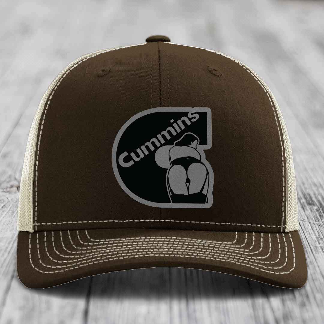 Tan trucker hat with black mesh back and gray Cummins logo patch on front.