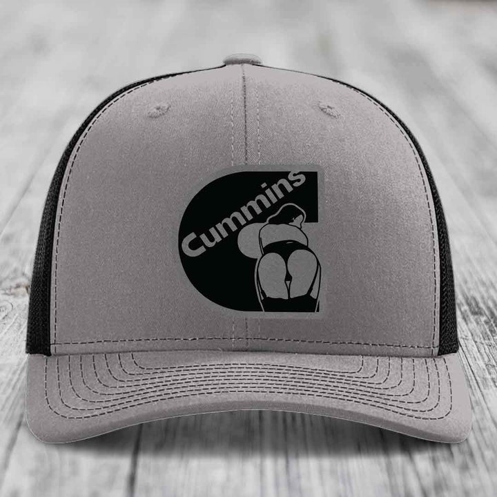 Grey trucker hat with blue mesh sides and a black Cummins logo patch on front.