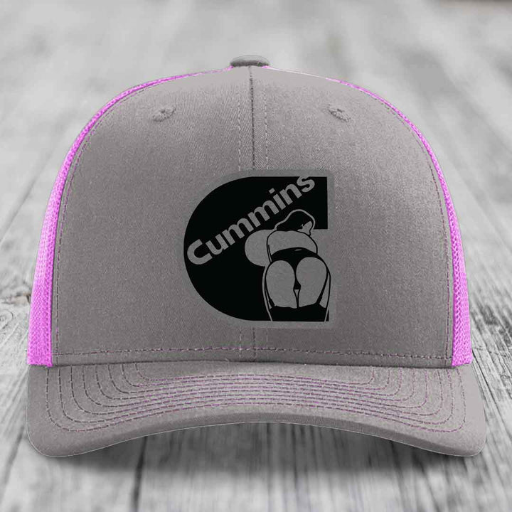Grey trucker hat with yellow mesh sides and stitching, featuring a black Cummins logo patch on front.