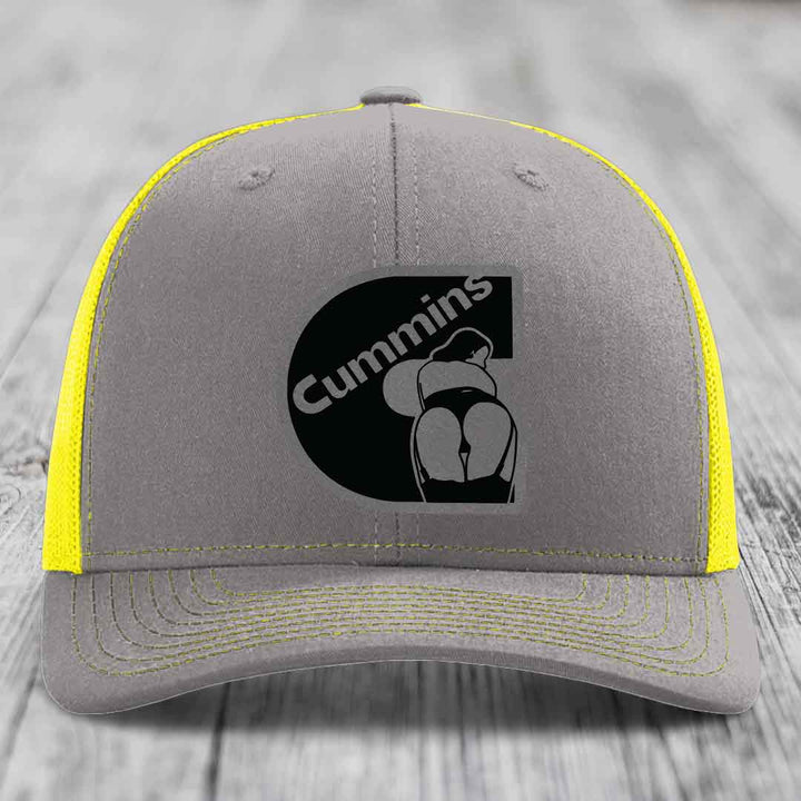 Brown trucker hat with Cummins logo patch on front, beige mesh back, stitched details.