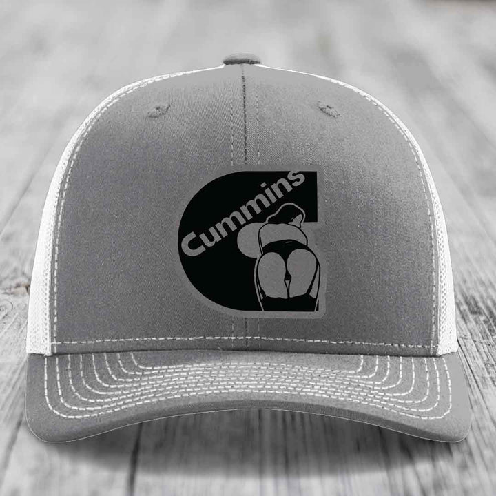 Pink trucker hat with black mesh back and gray Cummins logo patch on front.
