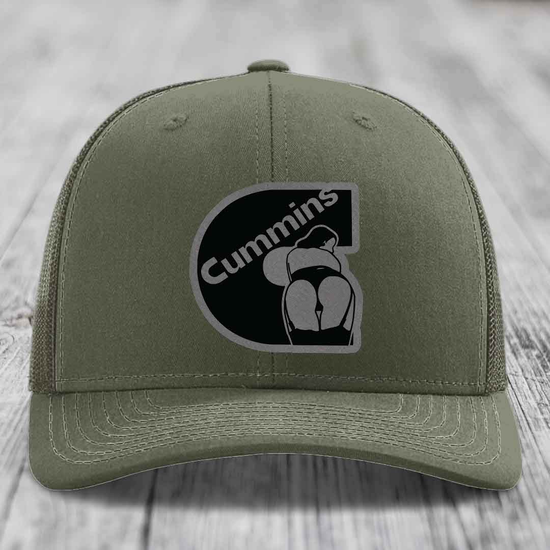 Olive green trucker hat with black mesh back and Cummins logo patch on front.