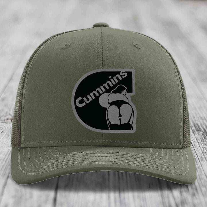 Olive green trucker hat with black mesh back and Cummins logo patch on front.