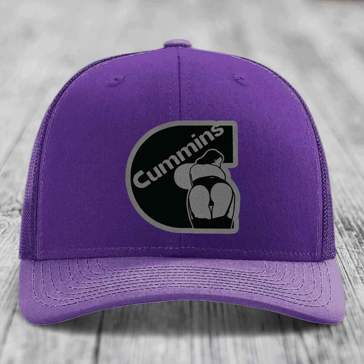 Red trucker hat with black mesh back and gray stitched Cummins logo patch on front.