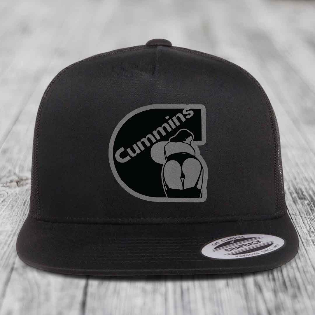 Black and white trucker hat with Cummins logo patch on front, flat brim, snapback closure.
