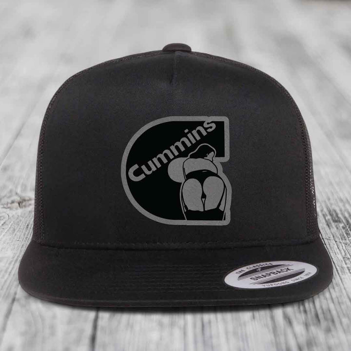 Black and white trucker hat with Cummins logo patch on front, flat brim, snapback closure.
