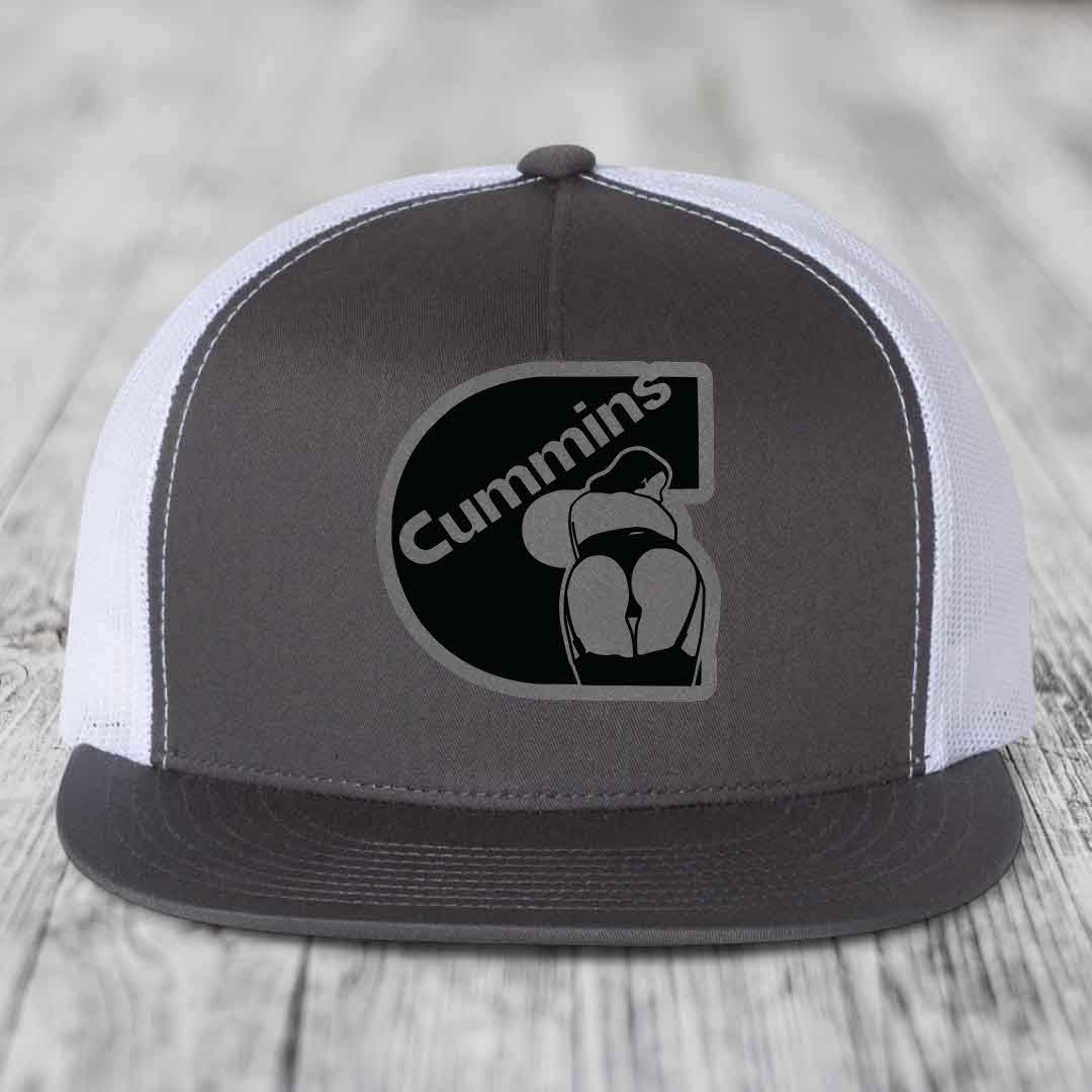 Black snapback trucker hat with Cummins logo patch on front, featuring a stylized &