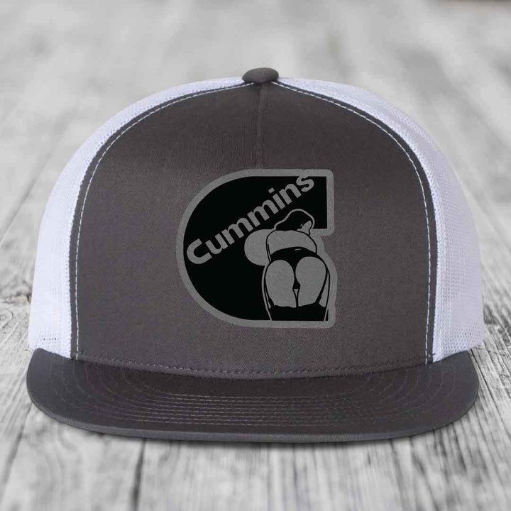 Black snapback trucker hat with Cummins logo patch on front, featuring a stylized &