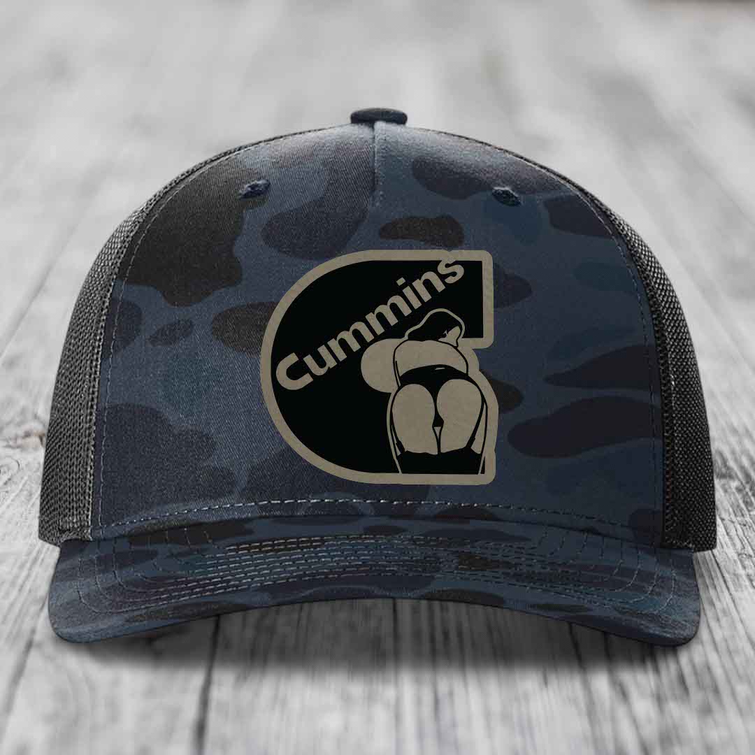 Camouflage trucker hat with black Cummins logo patch on front.