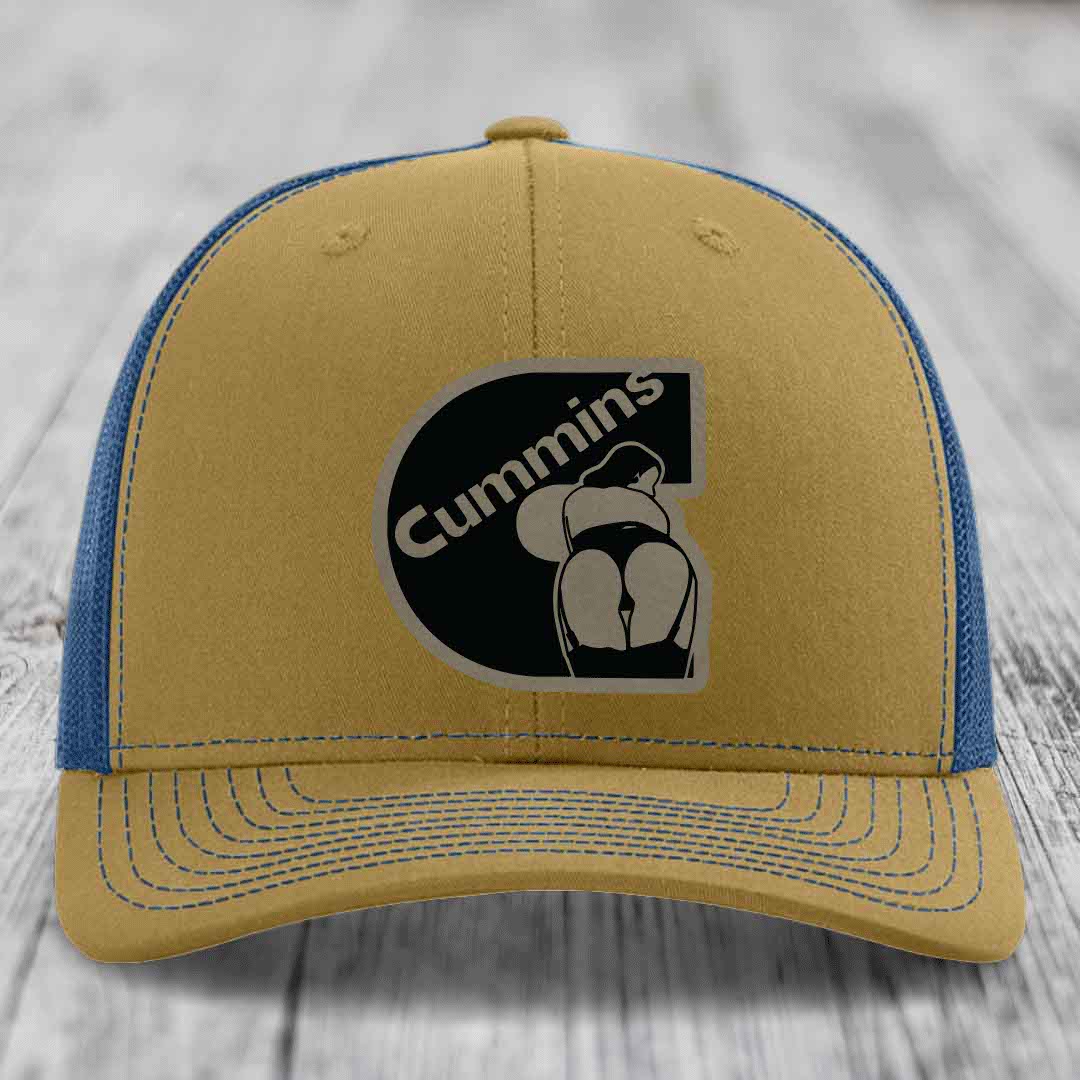 Black trucker hat with Cummins logo patch on front, resting on wooden surface.