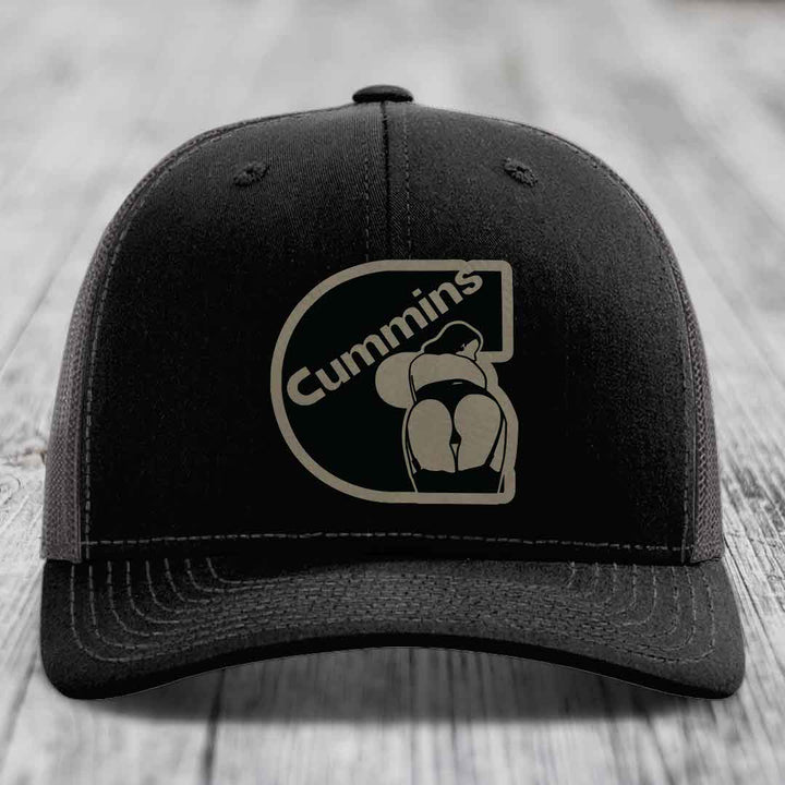 Black trucker hat with white stitching and a Cummins logo patch on the front.