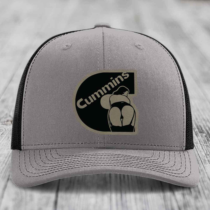 Grey trucker hat with blue mesh sides and a black Cummins logo patch on front.