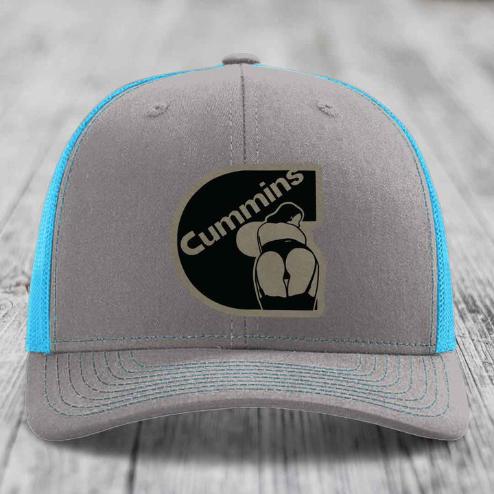 Grey trucker hat with neon green mesh and stitching, featuring a black Cummins logo patch.