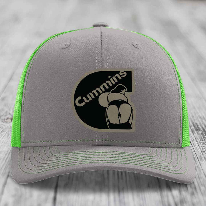 Grey trucker hat with orange mesh back and Cummins logo patch on front.