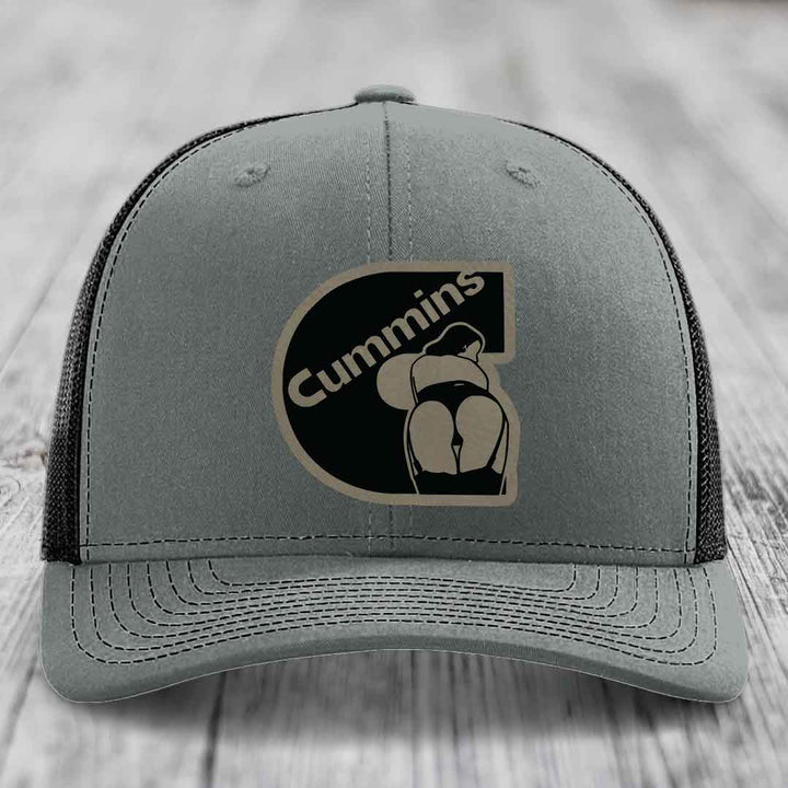 Grey trucker hat with white mesh back and embroidered Cummins logo patch.