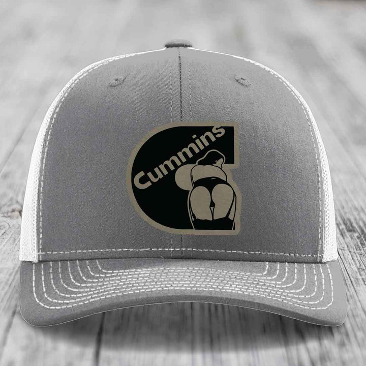 Pink trucker hat with black mesh back and gray stitched details, featuring a Cummins logo patch.