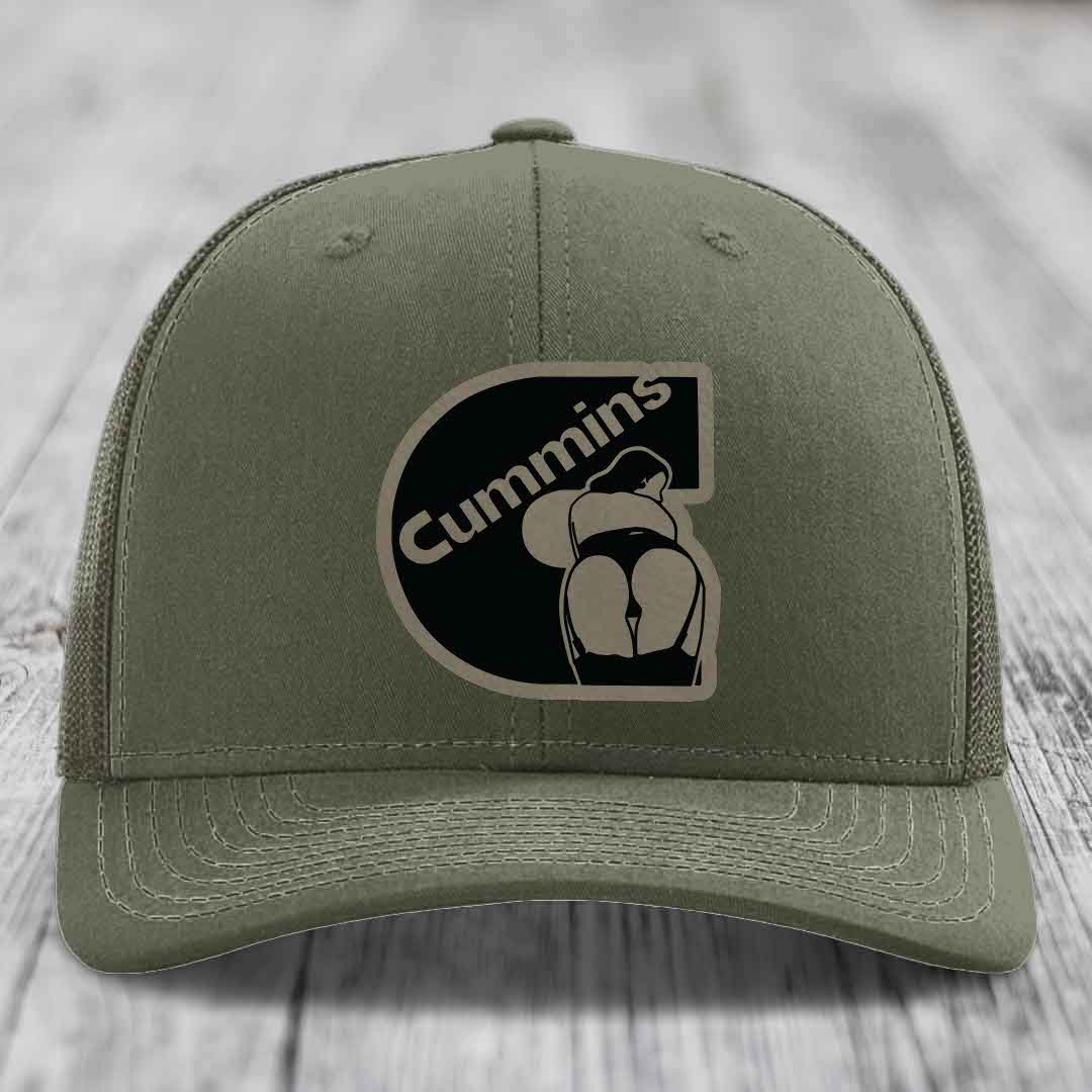 Olive green trucker hat with black mesh back and Cummins logo patch on front.