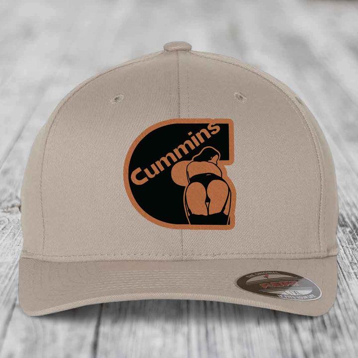 Beige baseball cap with black and tan Cummins logo patch featuring a stylized figure.
