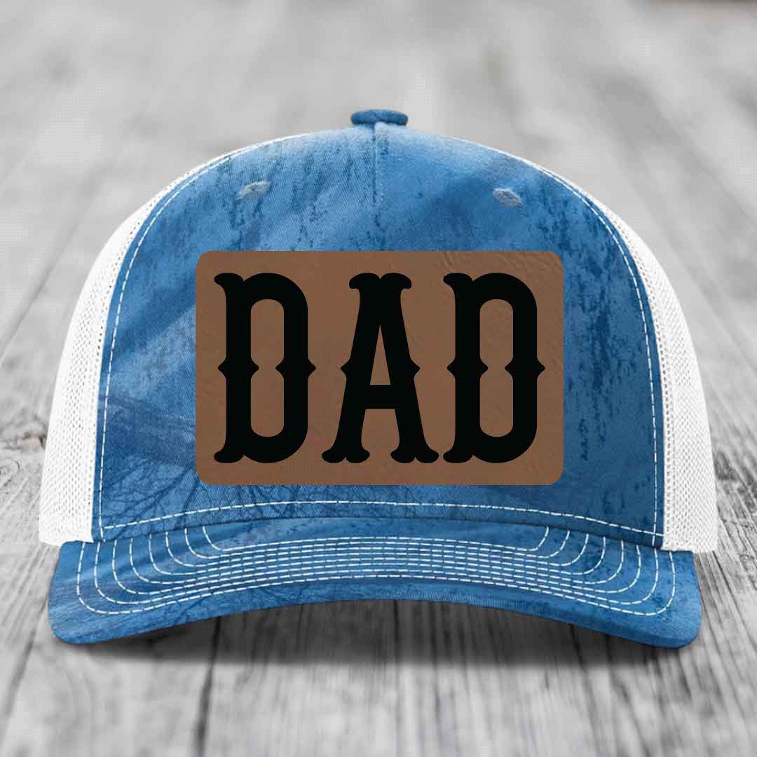 Camouflage trucker hat with brown leather patch that says DAD in black letters.