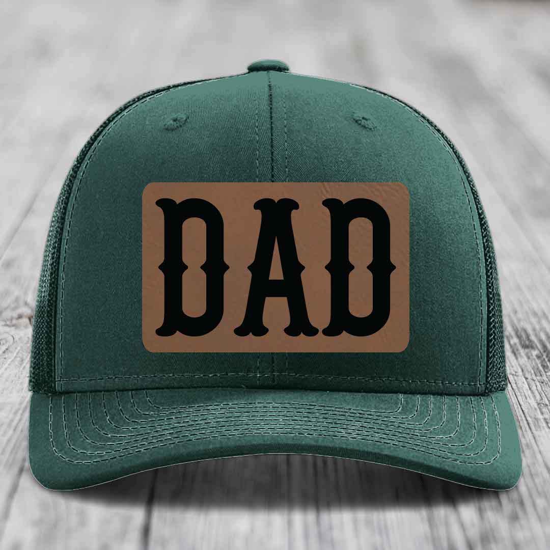 Grey trucker hat with brown leather patch that says DAD in black letters.