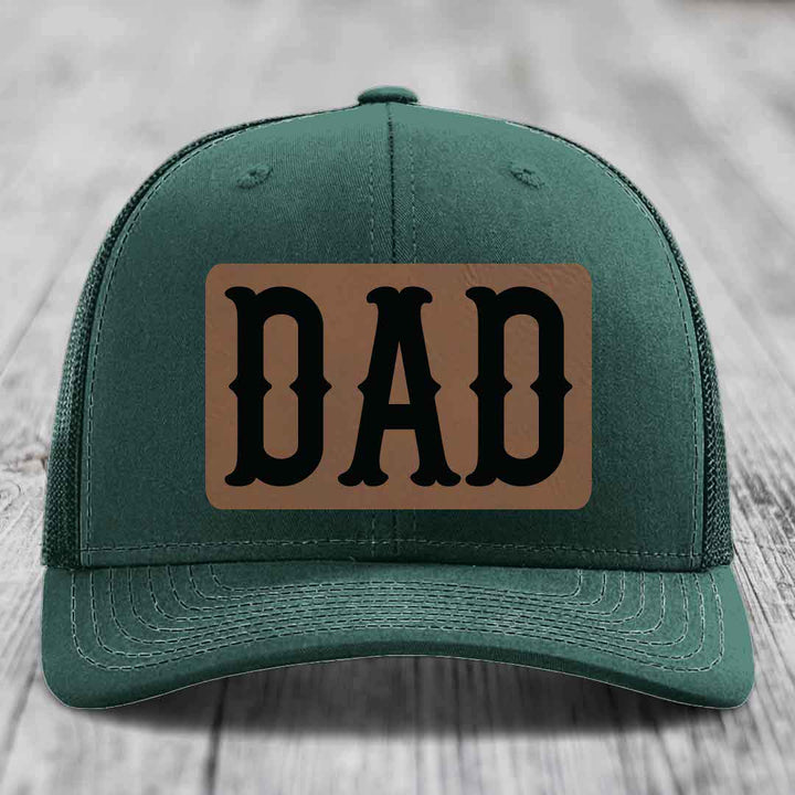 Grey trucker hat with brown leather patch that says DAD in black letters.