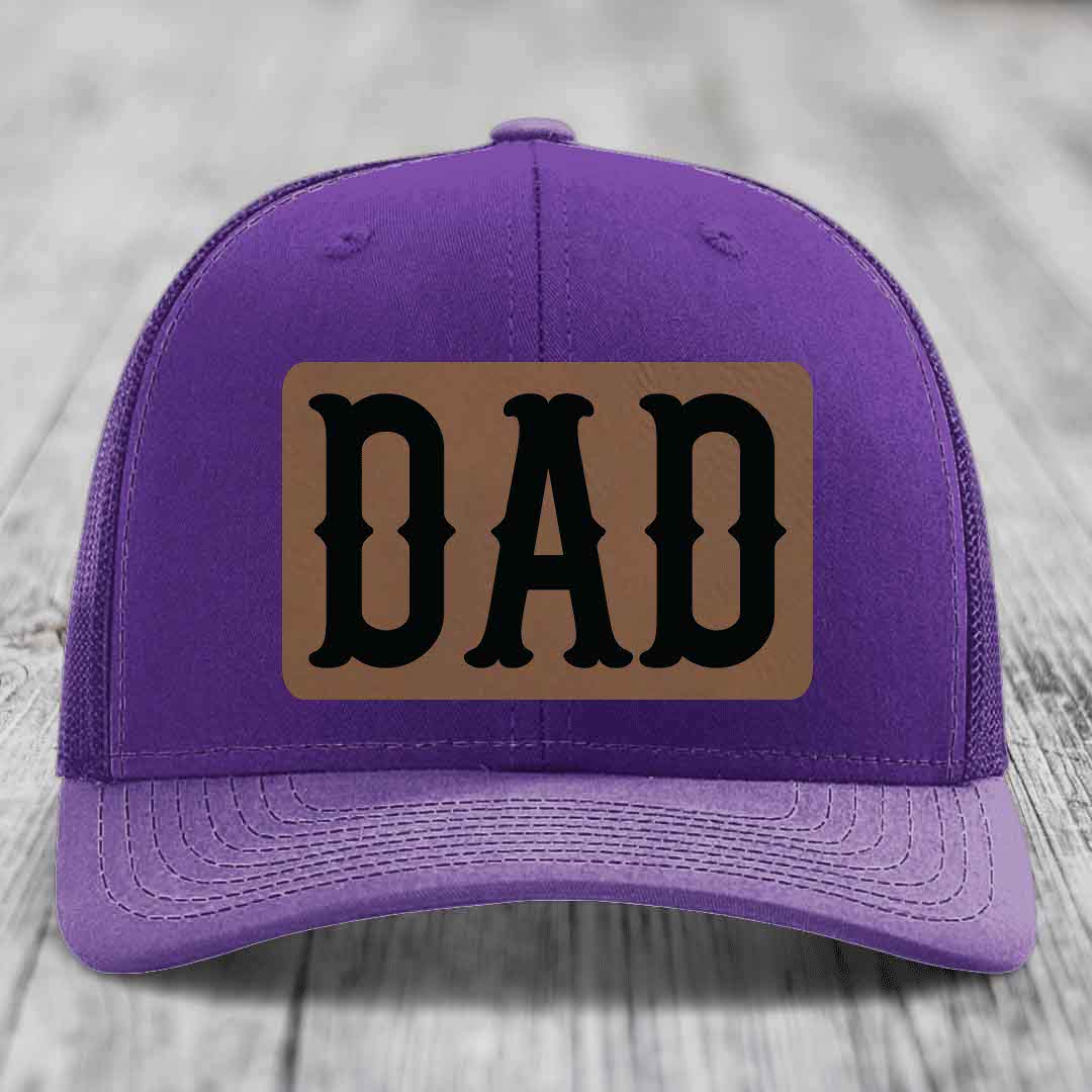 Red trucker hat with black mesh back and a brown leatherette patch that says &