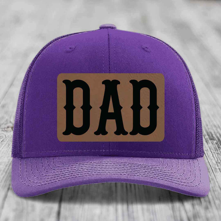Red trucker hat with black mesh back and a brown leatherette patch that says &