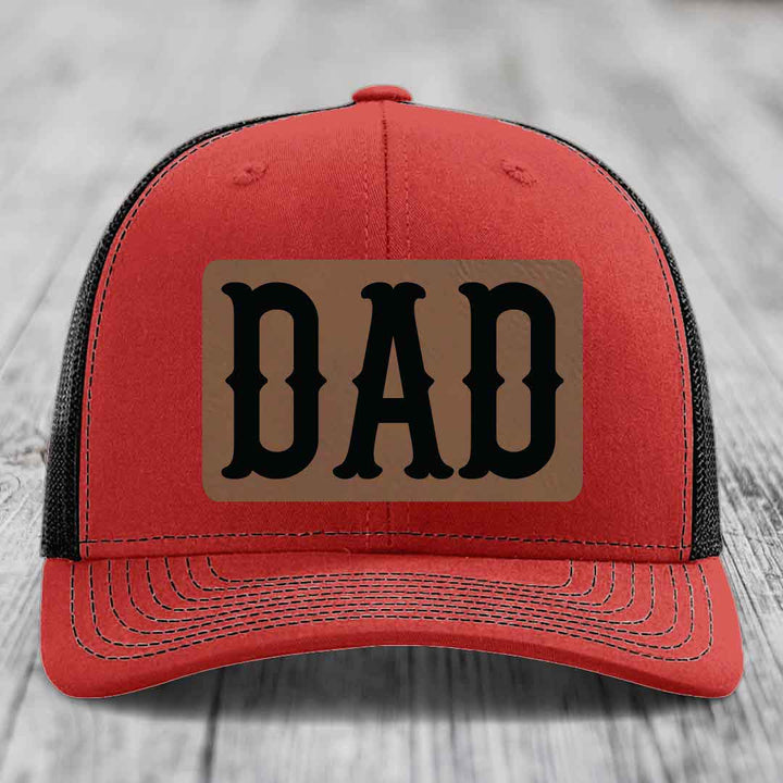 Blue trucker hat with brown leather patch that says DAD in black letters.