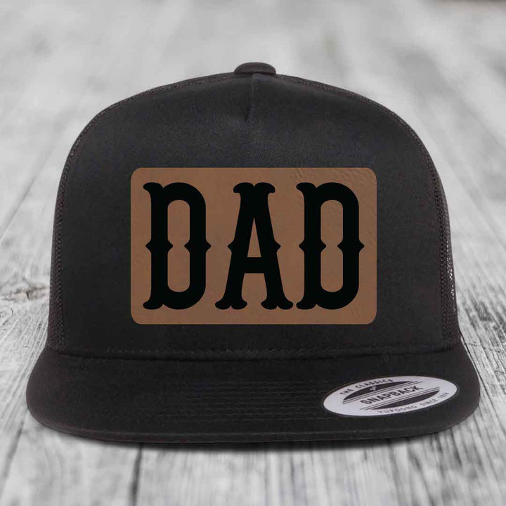 Black and white trucker hat with brown leather patch that says DAD in black letters.