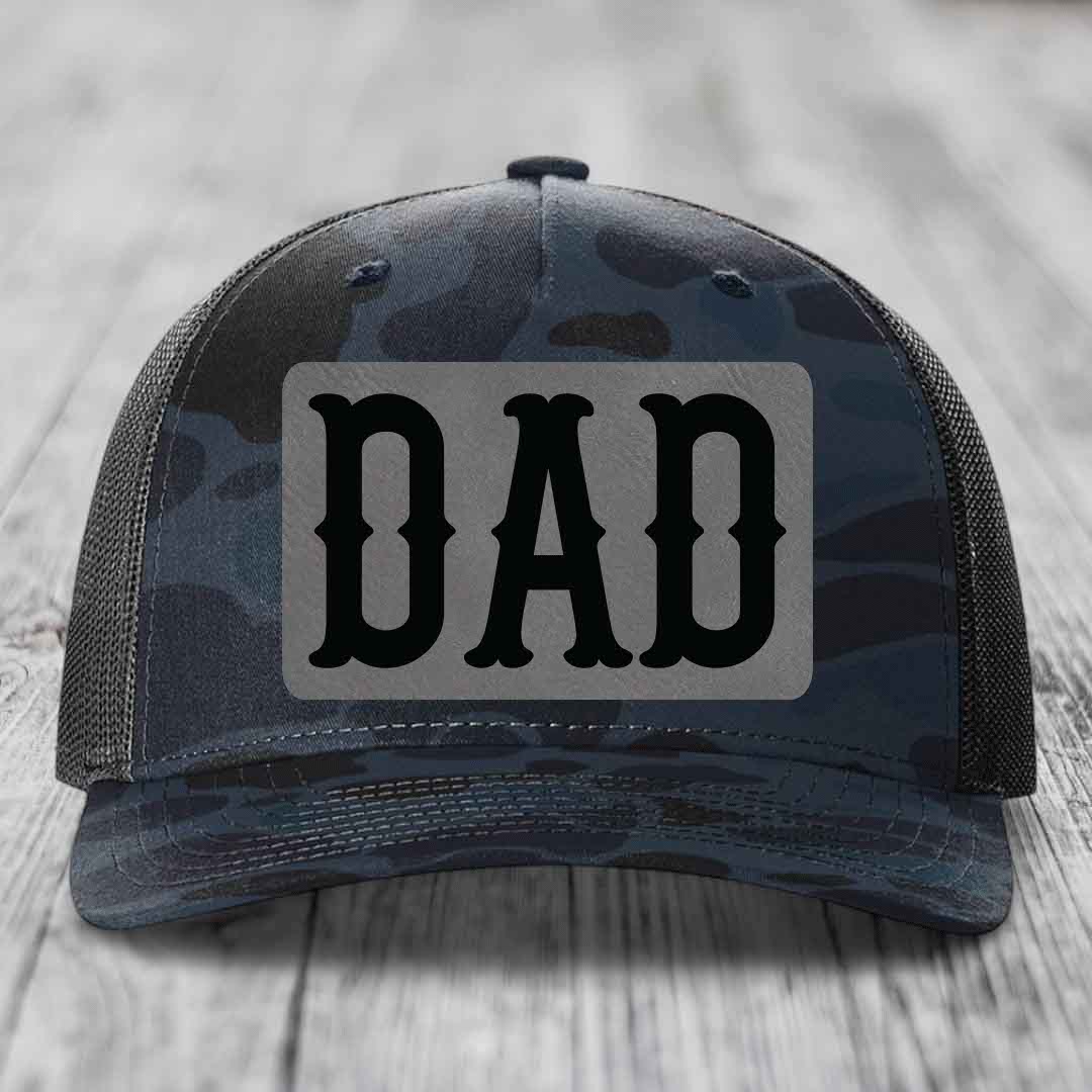 Camouflage trucker hat with a grey patch featuring the word &