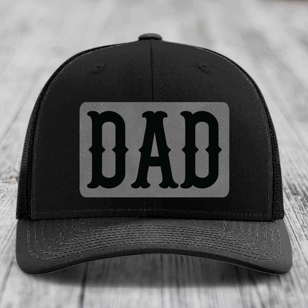 Tan and blue trucker hat with a grey leatherette patch that says DAD in black letters.