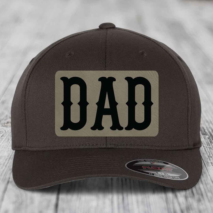 Brown dad hat with black leatherette patch and Flexfit label on brim.