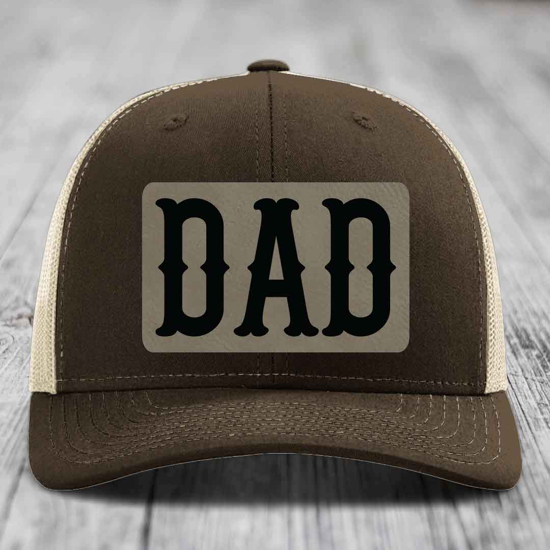 Green trucker hat with a beige leatherette patch that says DAD in black letters.
