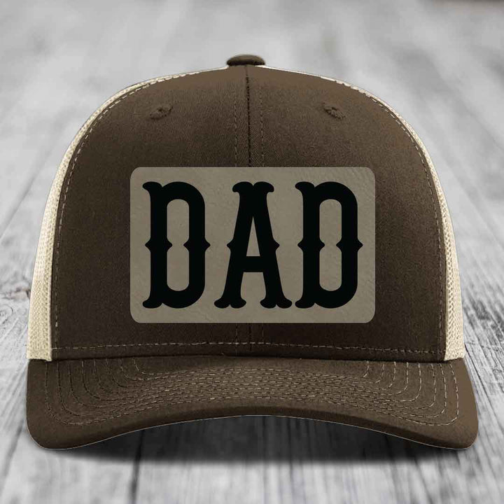 Green trucker hat with a beige leatherette patch that says DAD in black letters.