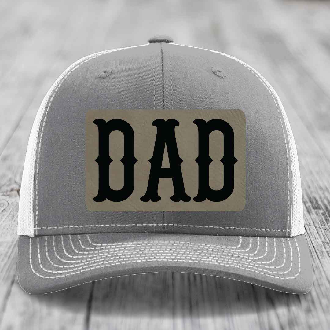 Pink trucker hat with black mesh back and gray leather patch that says DAD in black letters.