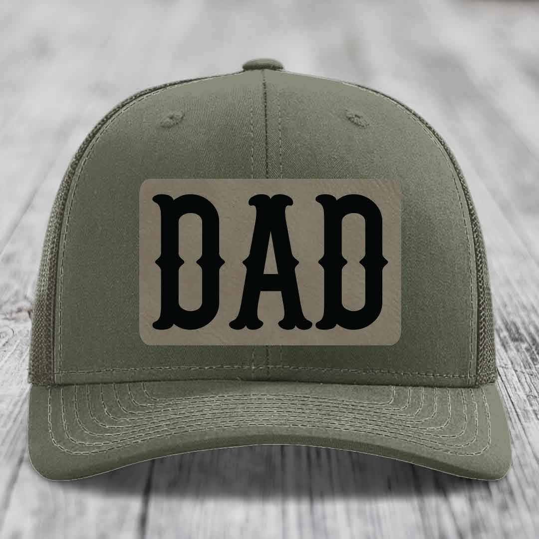 Olive green trucker hat with black mesh back and a beige leatherette patch that says &