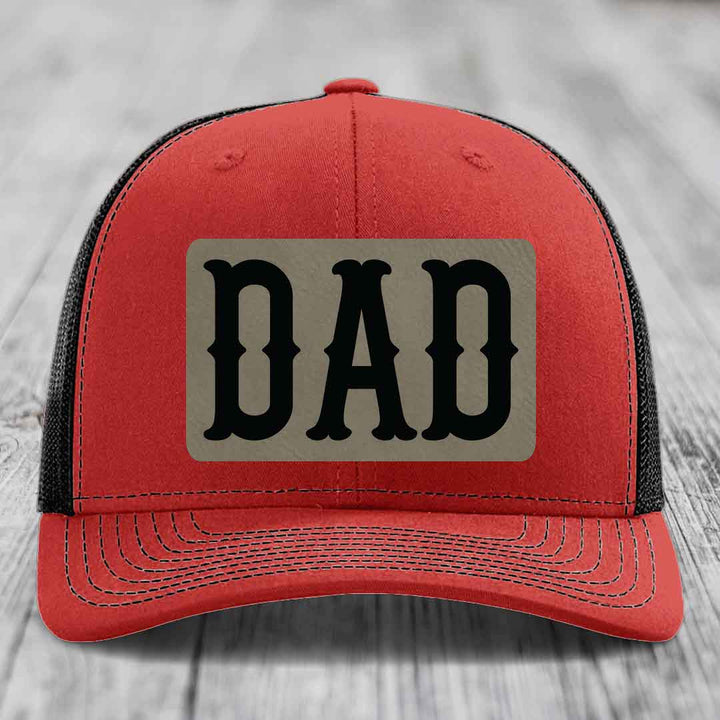 Blue trucker hat with black mesh back and a beige leatherette patch that says &
