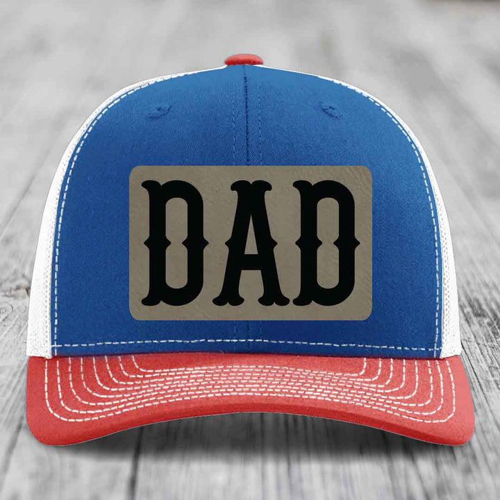 White trucker hat with a rectangular tan leatherette patch that says &