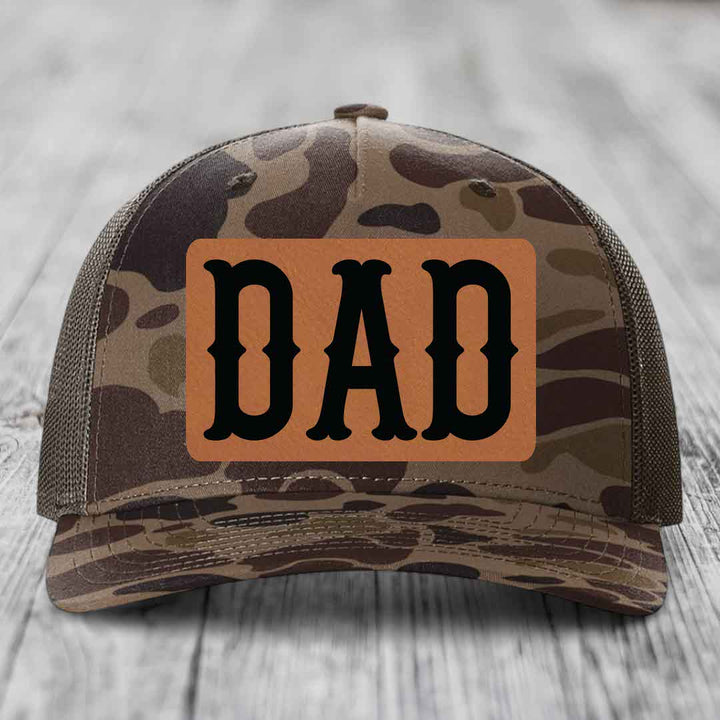 Camouflage trucker hat with brown leather patch reading &